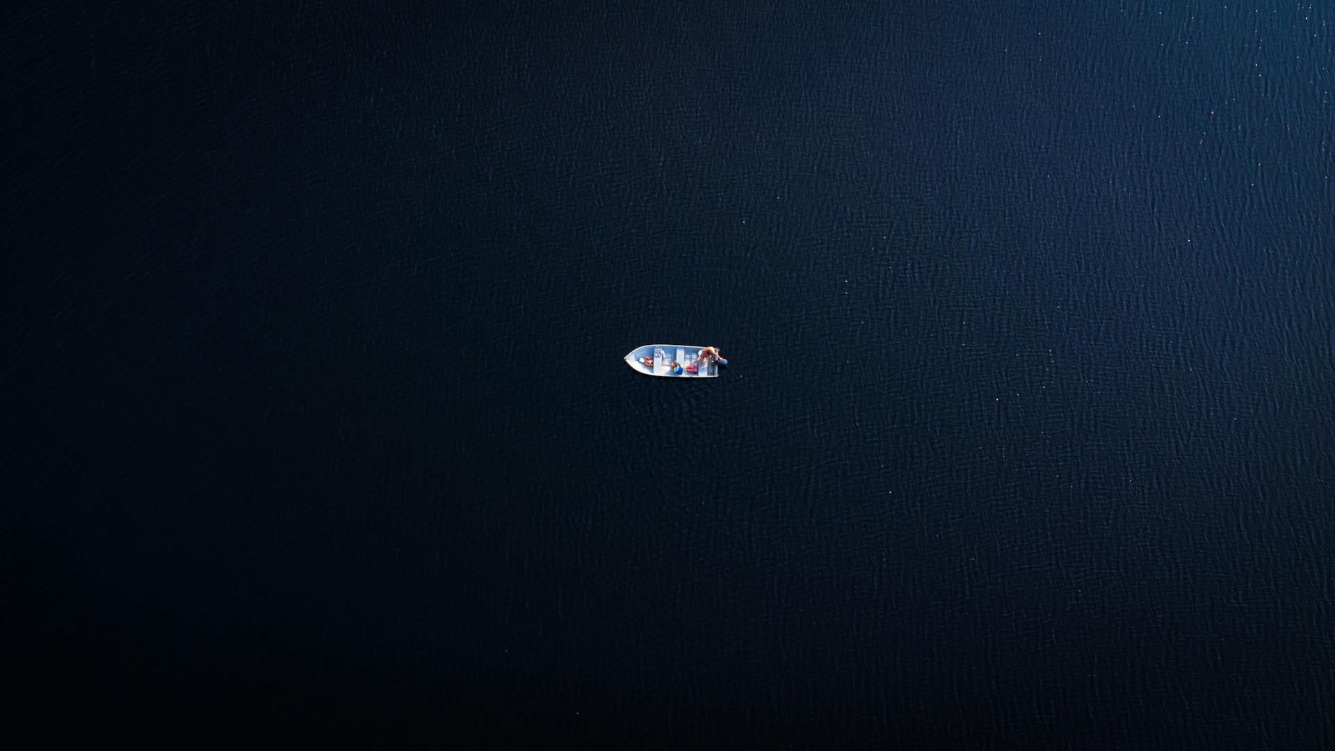 A solitary boat afloat in the calm, deep blue waters of Blackstone Lake, captured from above.