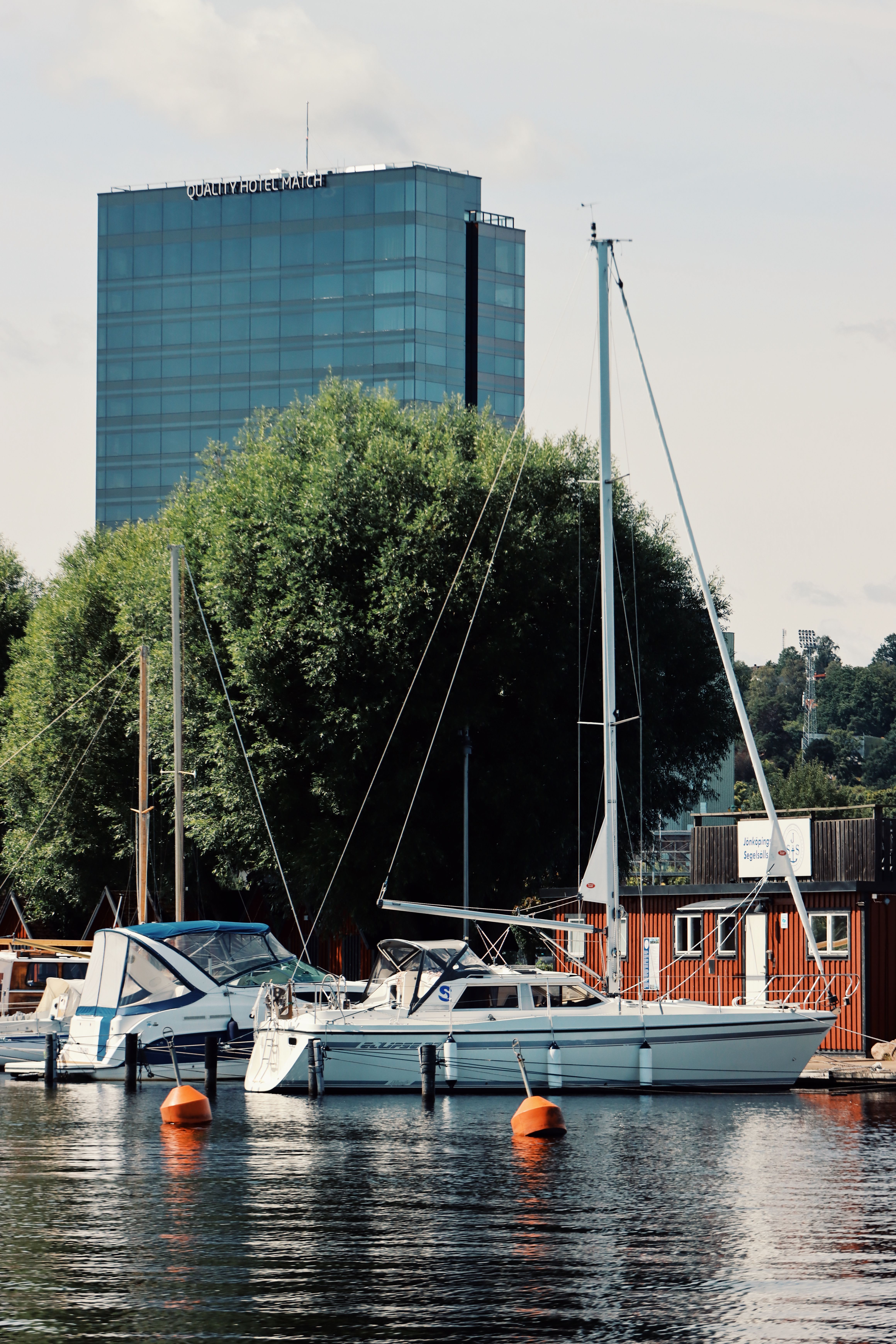Serene marina scene in Jönköping, Sweden with sailboats and a modern hotel. Ideal travel destination.