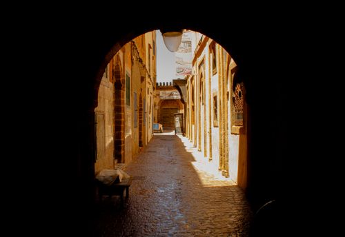 Free A sunlit alleyway in Essaouira, Morocco, showcasing traditional architecture and shadow play. Stock Photo
