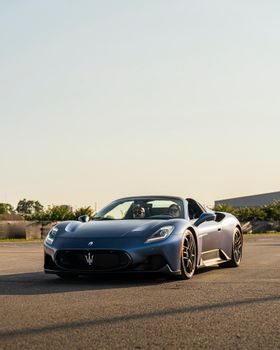 Sleek Maserati convertible on an open road during sunny summer day.