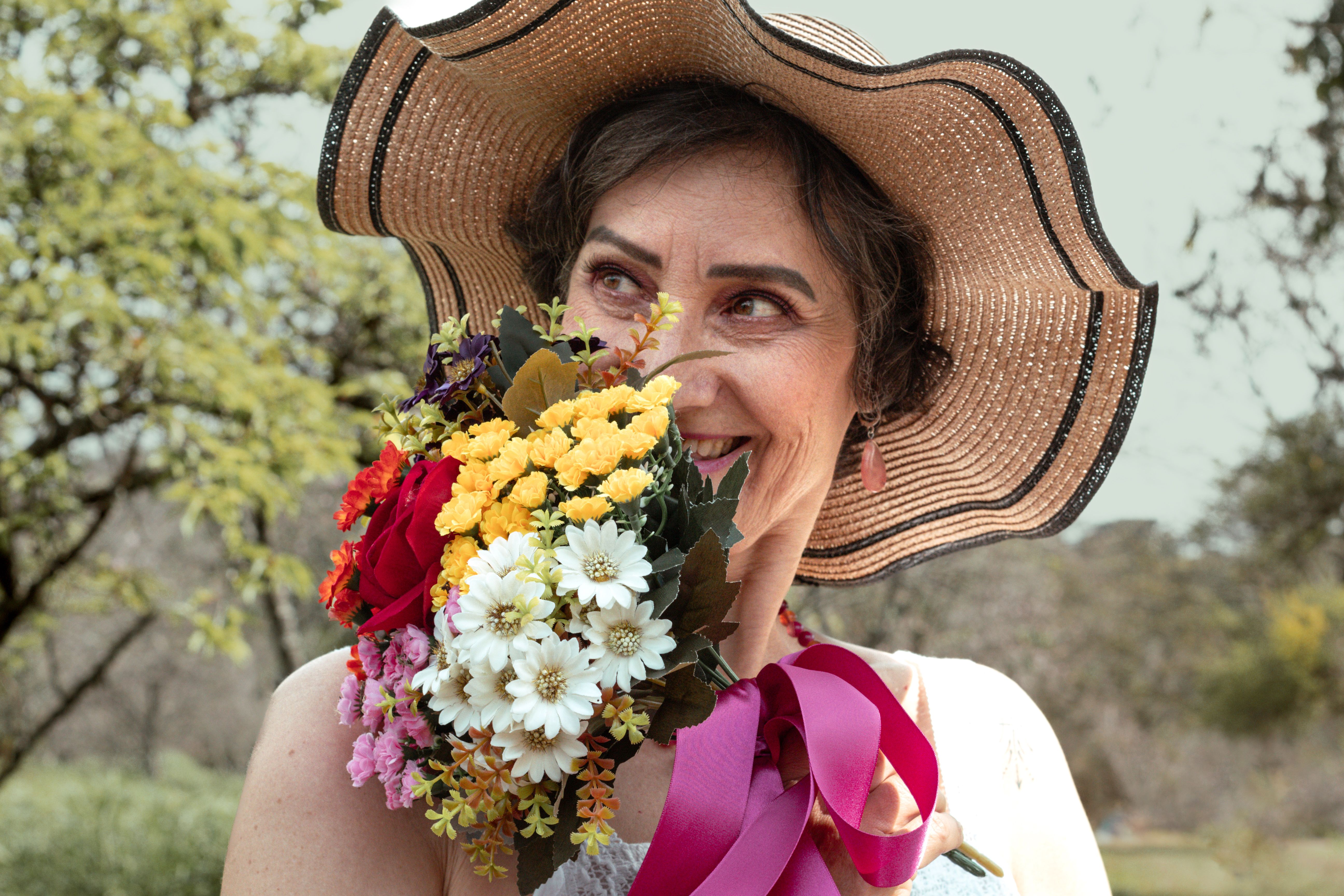 A woman in a hat holding a bouquet of flowers · Free Stock Photo