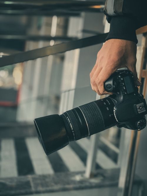 Free Close-up of a person holding a DSLR camera, showcasing urban photography. Stock Photo
