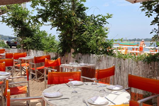 Charming outdoor dining area with orange chairs on Shelter Island beach.