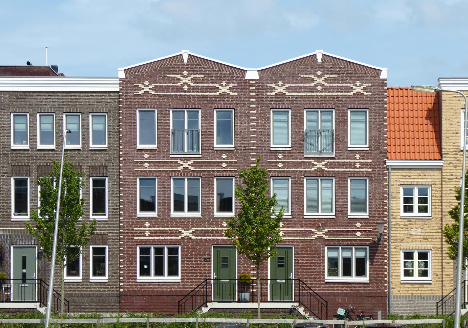 Symmetrical brick residential buildings with intricate geometric facades in a suburban neighborhood.