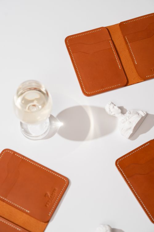 Free Elegant composition of leather wallets with wine glass and sculpture on a white background. Stock Photo