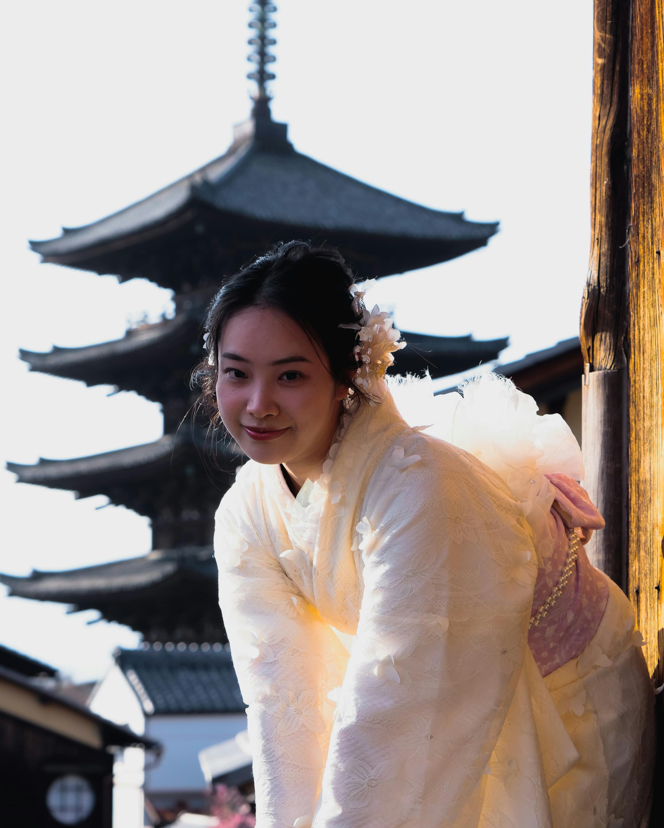 A woman in a traditional kimono poses near a historic pagoda in Tokyo, Japan, during daylight.