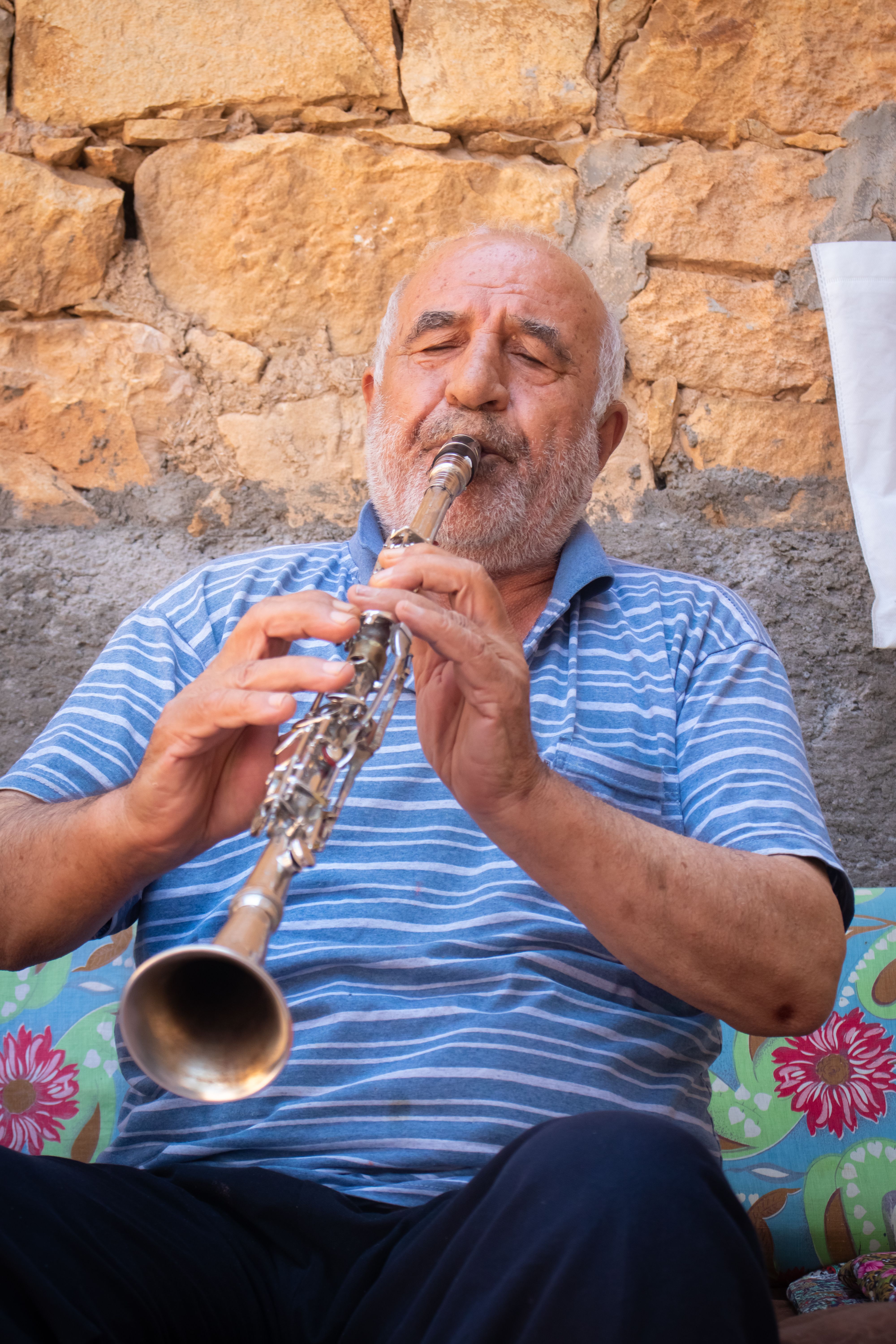 Senior man plays a woodwind instrument outdoors in Arapgir, Malatya, capturing a musical moment.