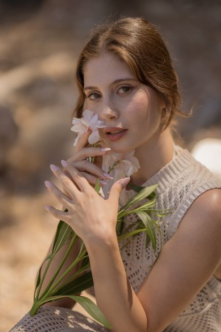 A serene portrait of a woman holding flowers outdoors, capturing elegance.