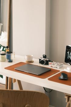 A clean and minimalist home office desk featuring a laptop, camera, and modern accessories.
