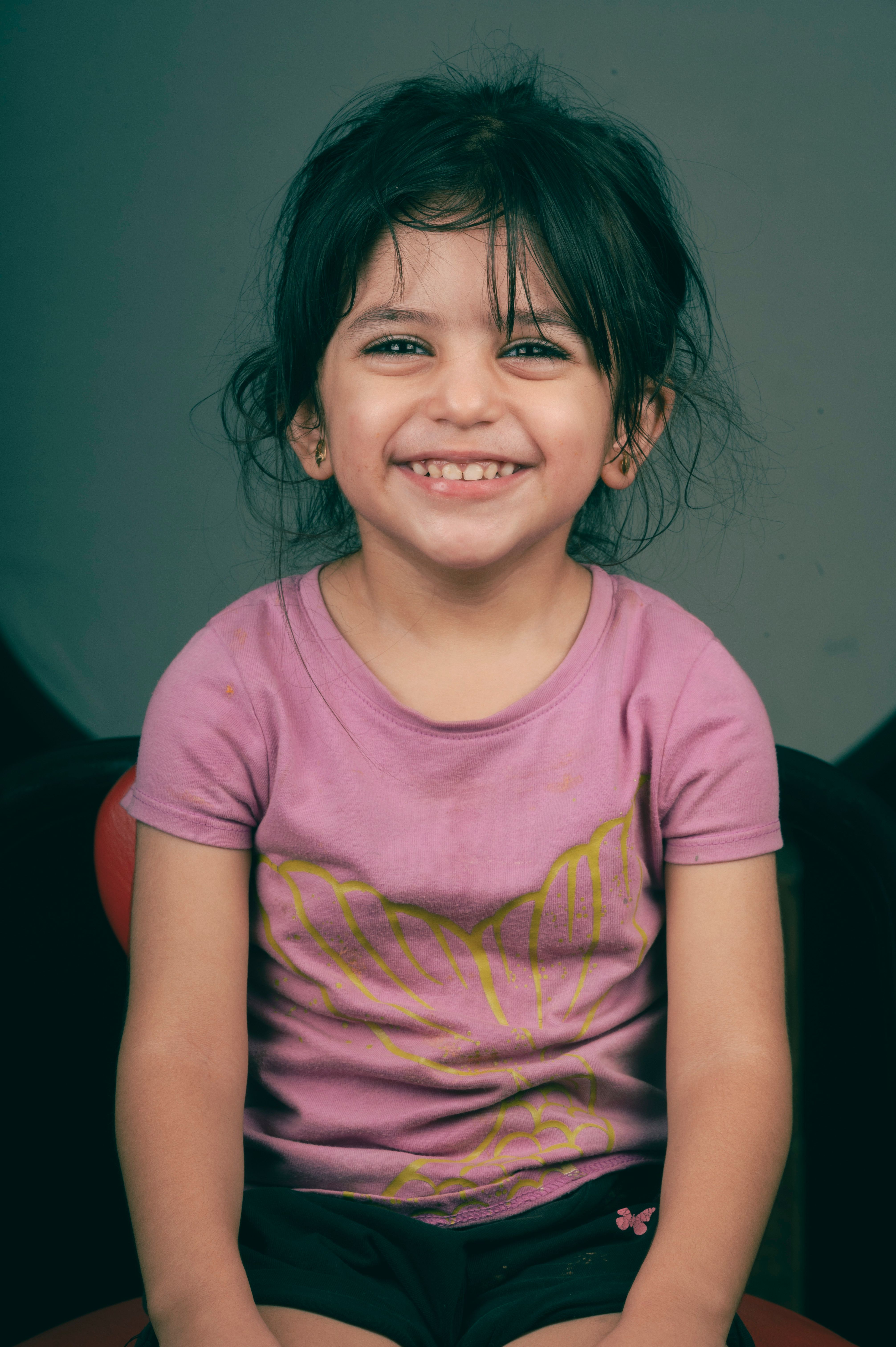 A smiling little girl sitting on a chair · Free Stock Photo