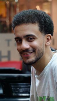 Portrait of a smiling young man with facial hair in an indoor setting, exuding confidence and warmth.