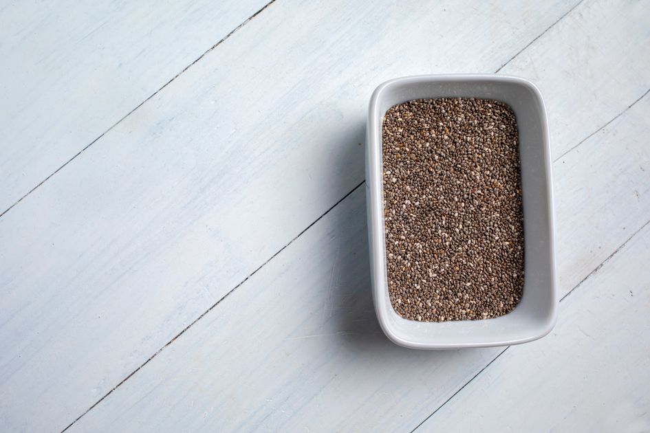 Sementes de chia pretas em close-up sobre superfície branca — textura detalhada da semente
