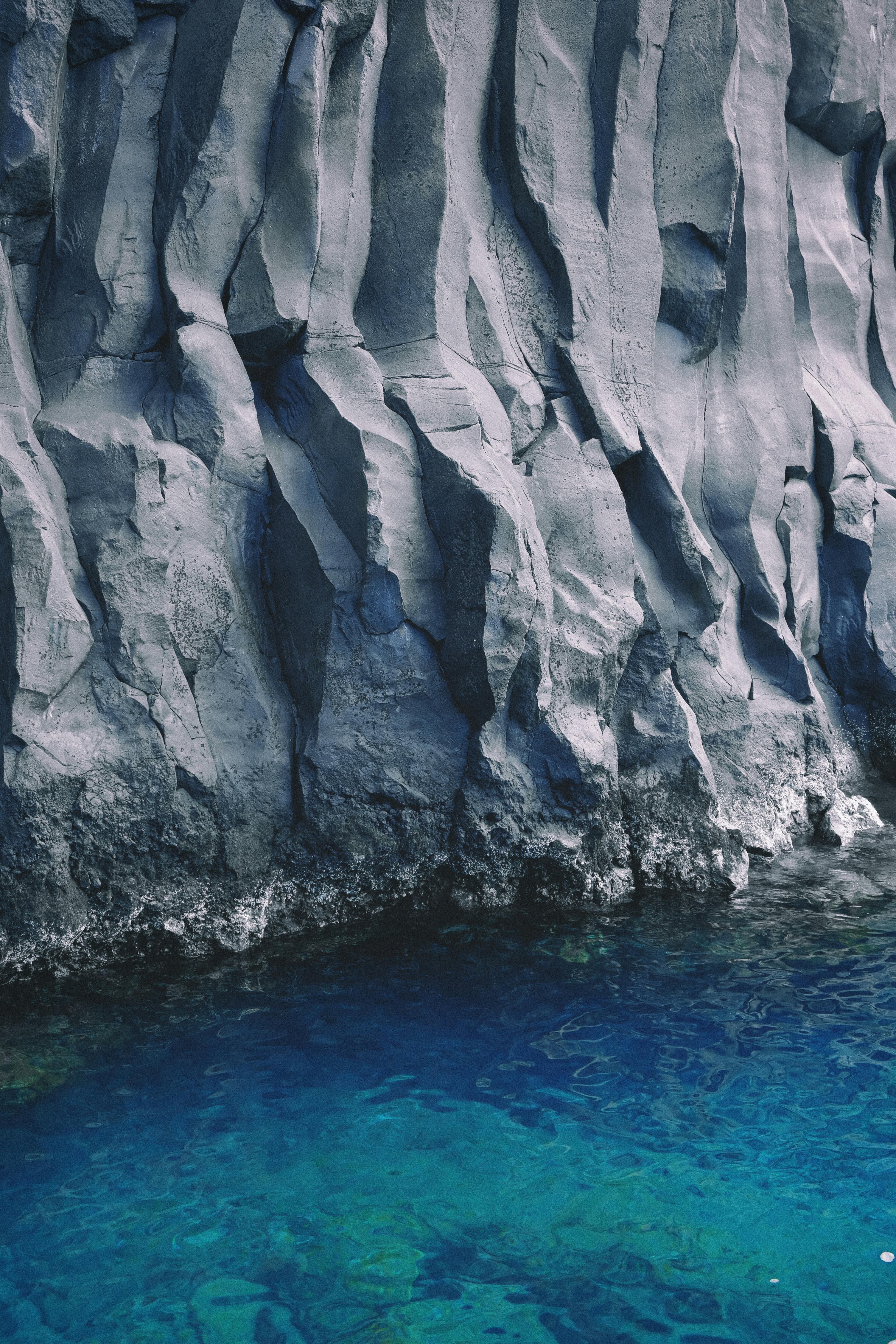Spectacular rock cliffs rise above vivid blue water, showcasing nature's art.