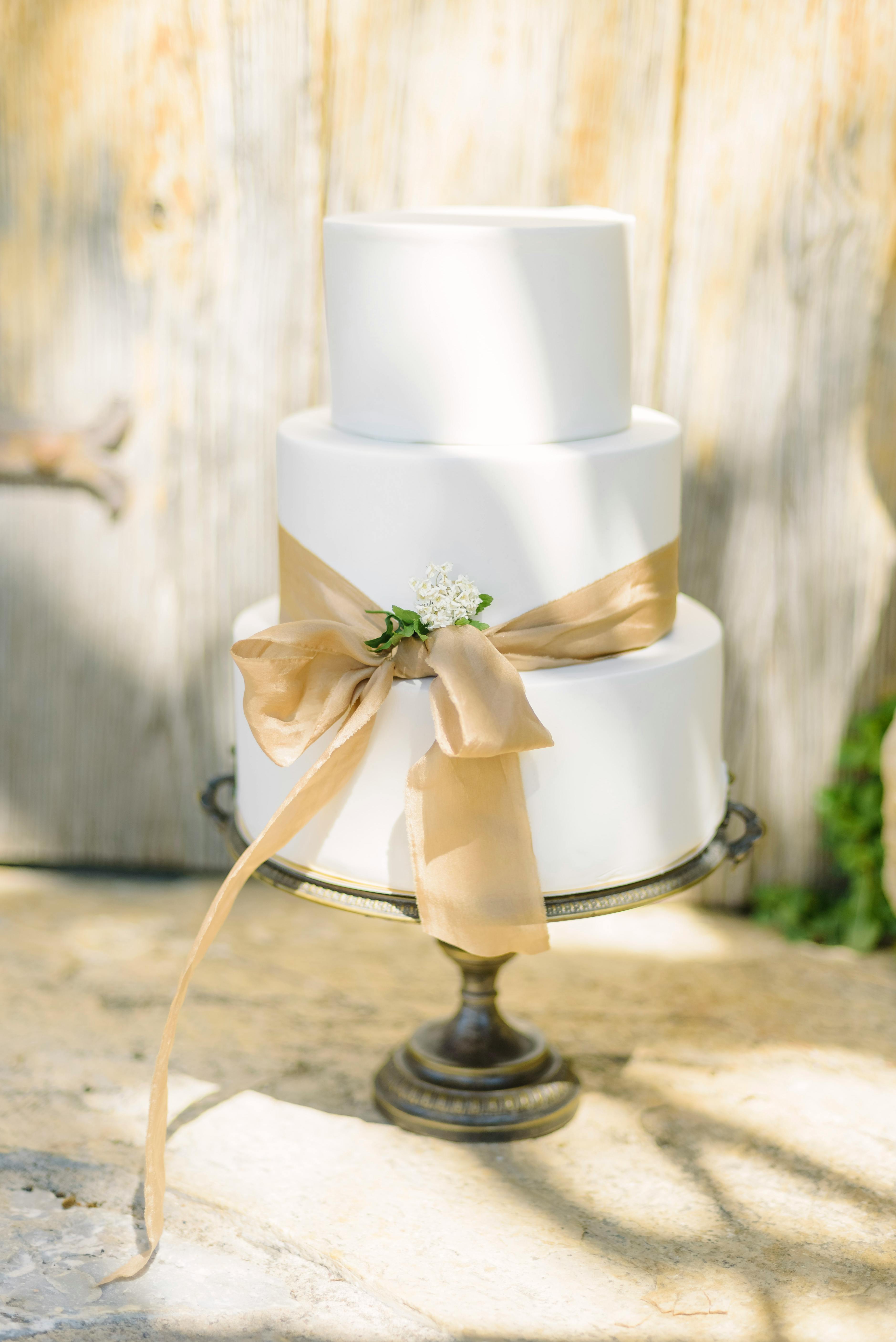 A luxurious three-tier wedding cake with floral decor in a rustic setting.