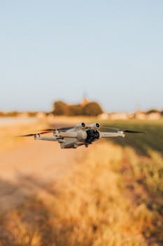 Aerial view of a drone flying over a rural field during sunset.