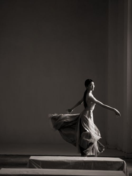 Free Monochrome photo of a woman dancing gracefully in an elegant flowing dress indoors. Stock Photo
