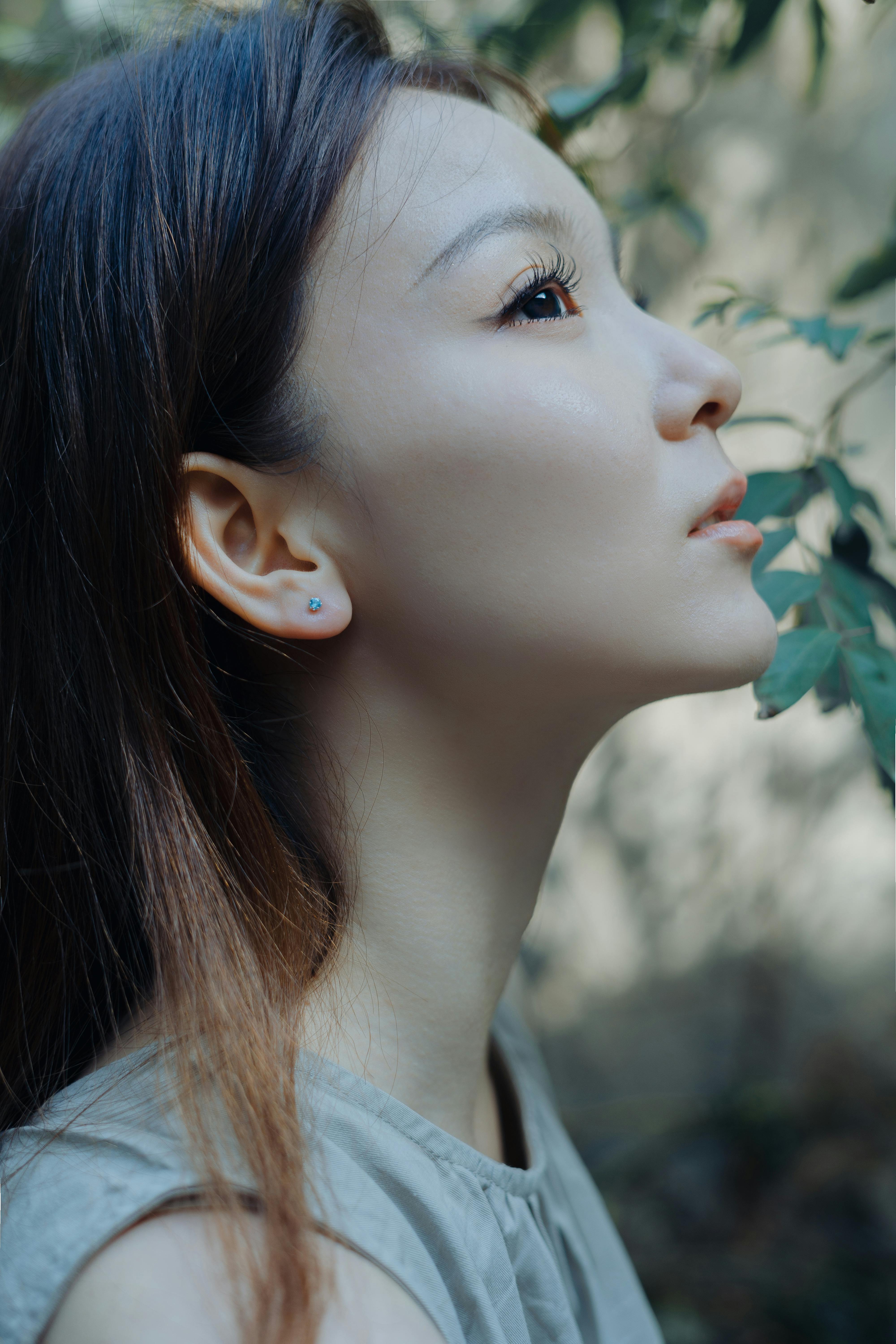 Profile photo of a woman outdoors with a serene expression beside foliage.