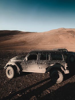 Dusty jeep parked on rough terrain in Leh during sunset, showcasing adventure travel vibes.