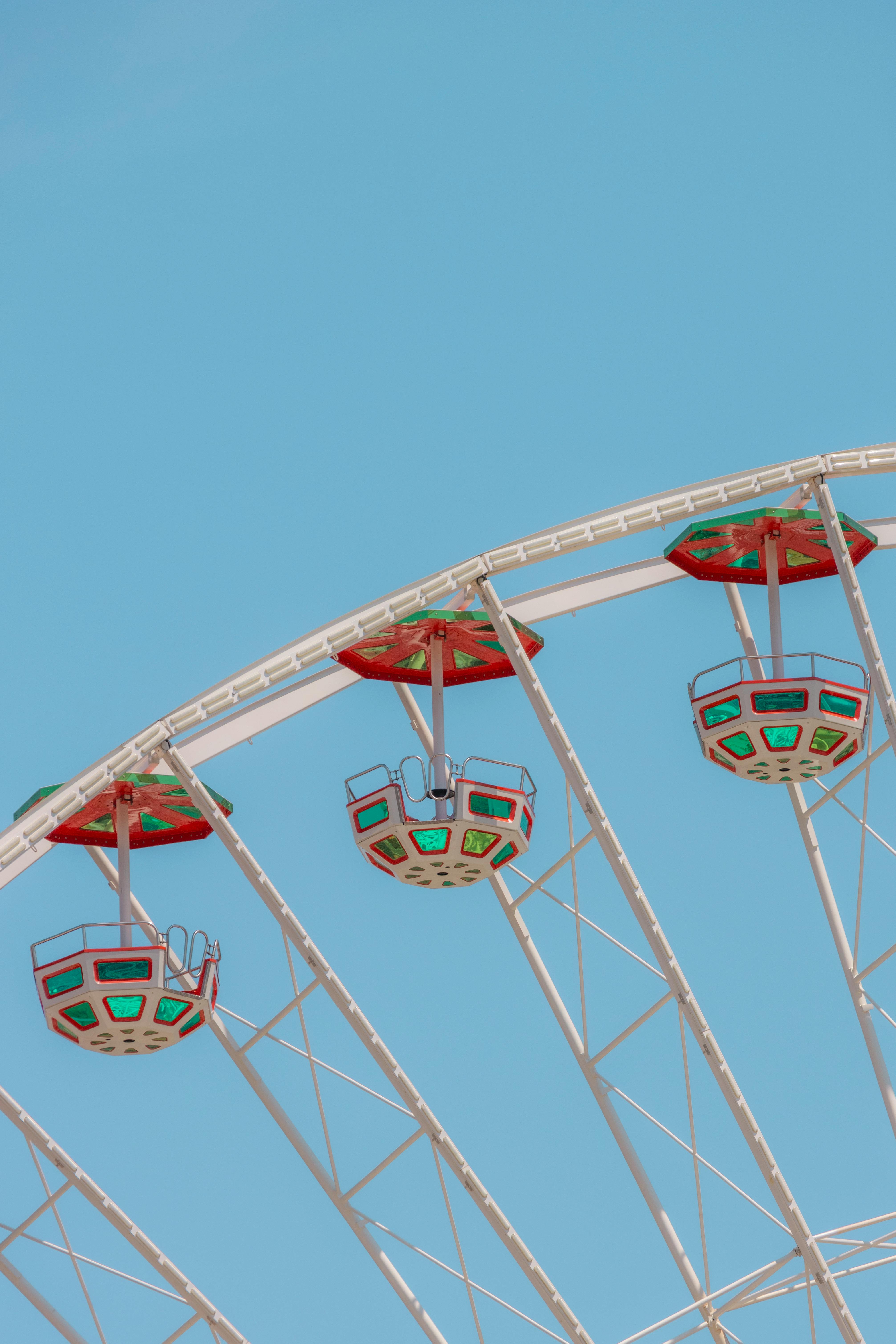 A vibrant Ferris wheel with colorful cabins set against a bright blue sky, capturing the essence of leisure and fun.