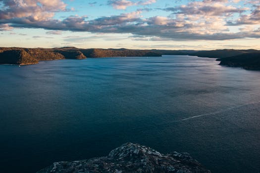 A panoramic view of a calm sea with mountains at sunset, offering a peaceful seascape.
