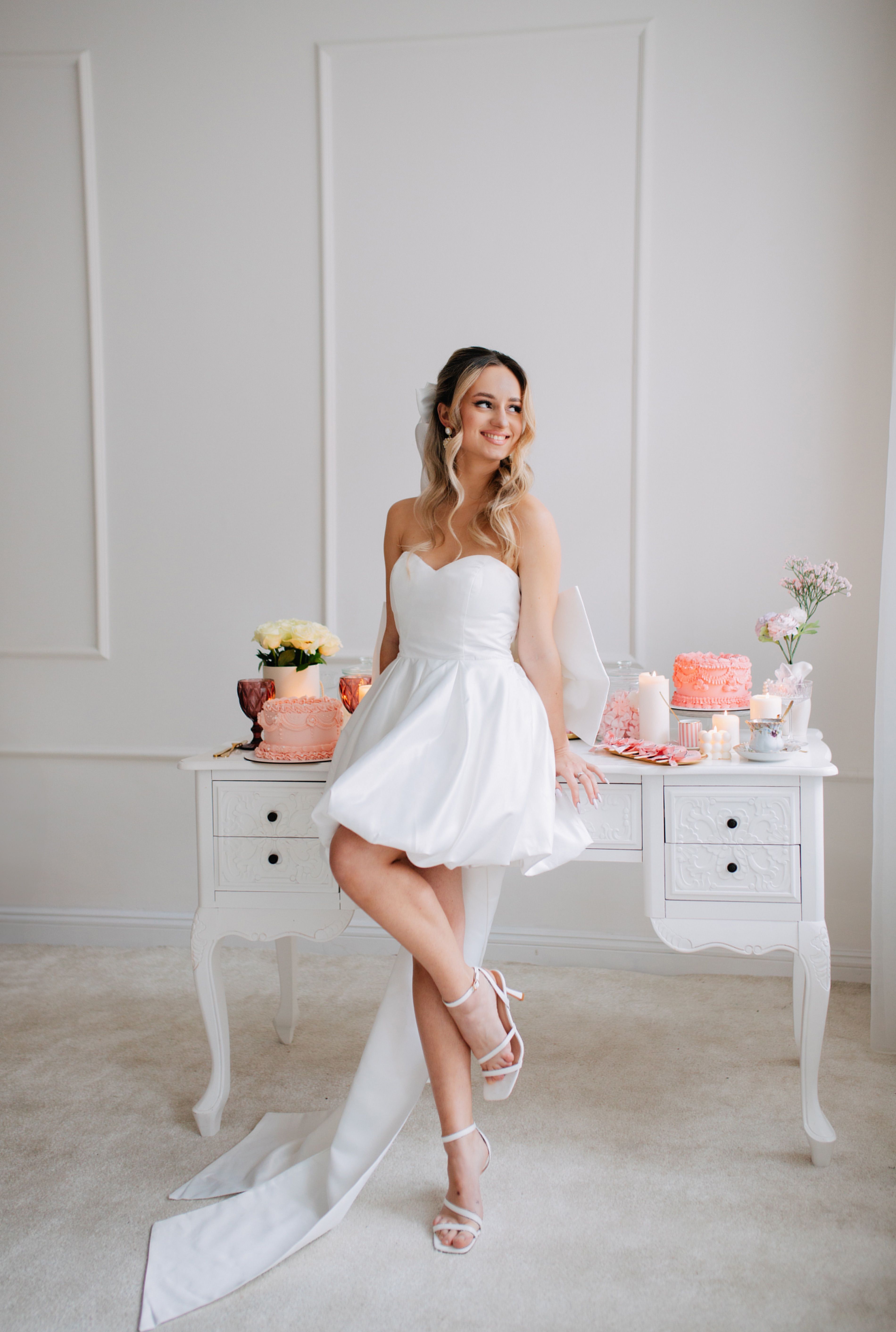 A woman in a white dress sitting on a table · Free Stock Photo