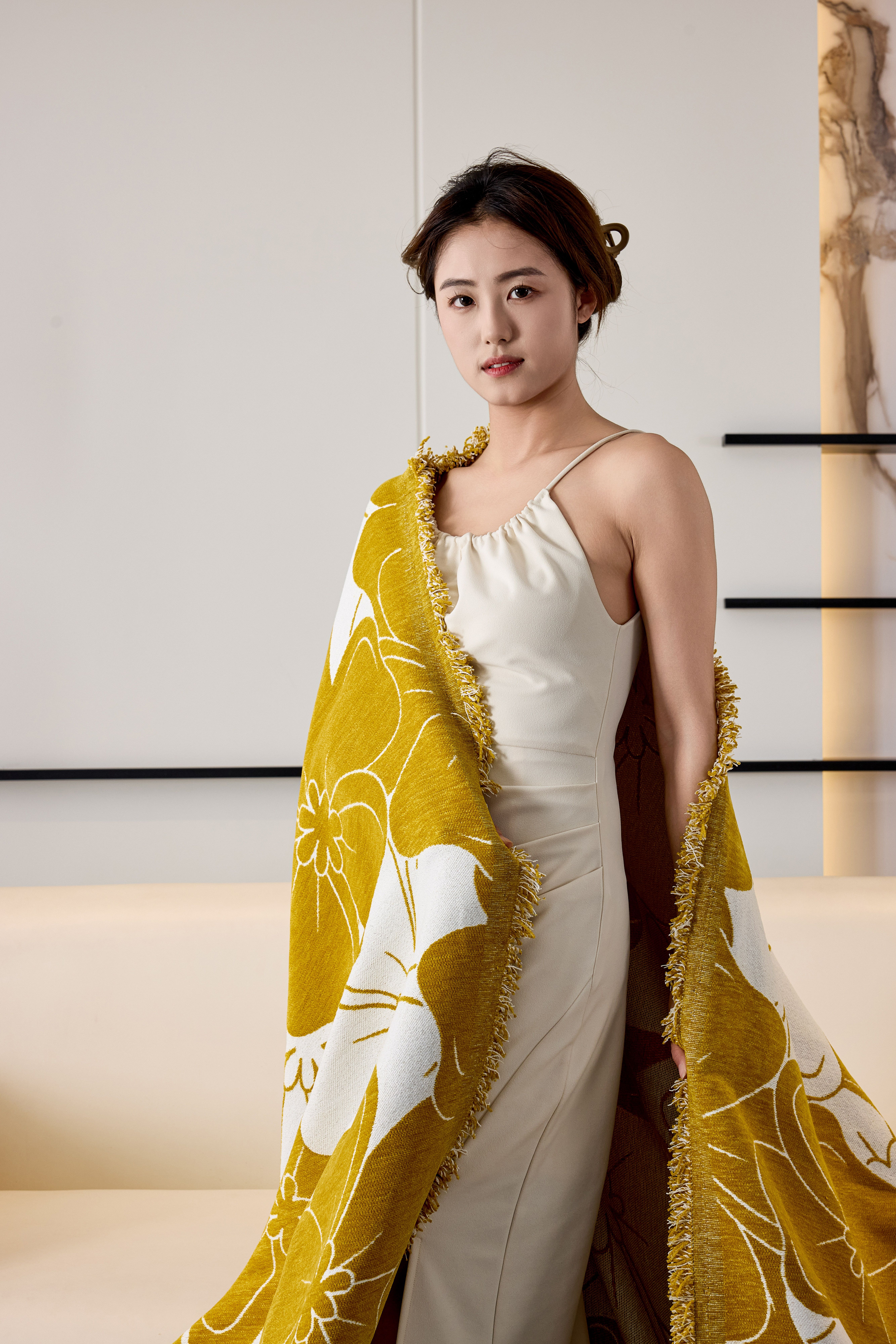 A stylish woman in a dress wrapped in a floral blanket, radiating elegance.