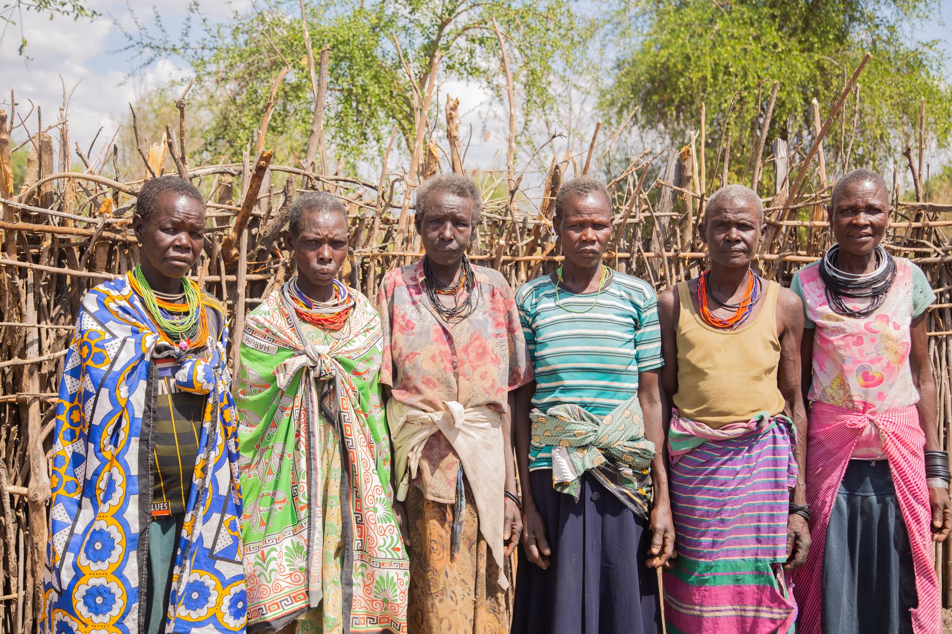 Group of tribal women in traditional attire standing outdoors.