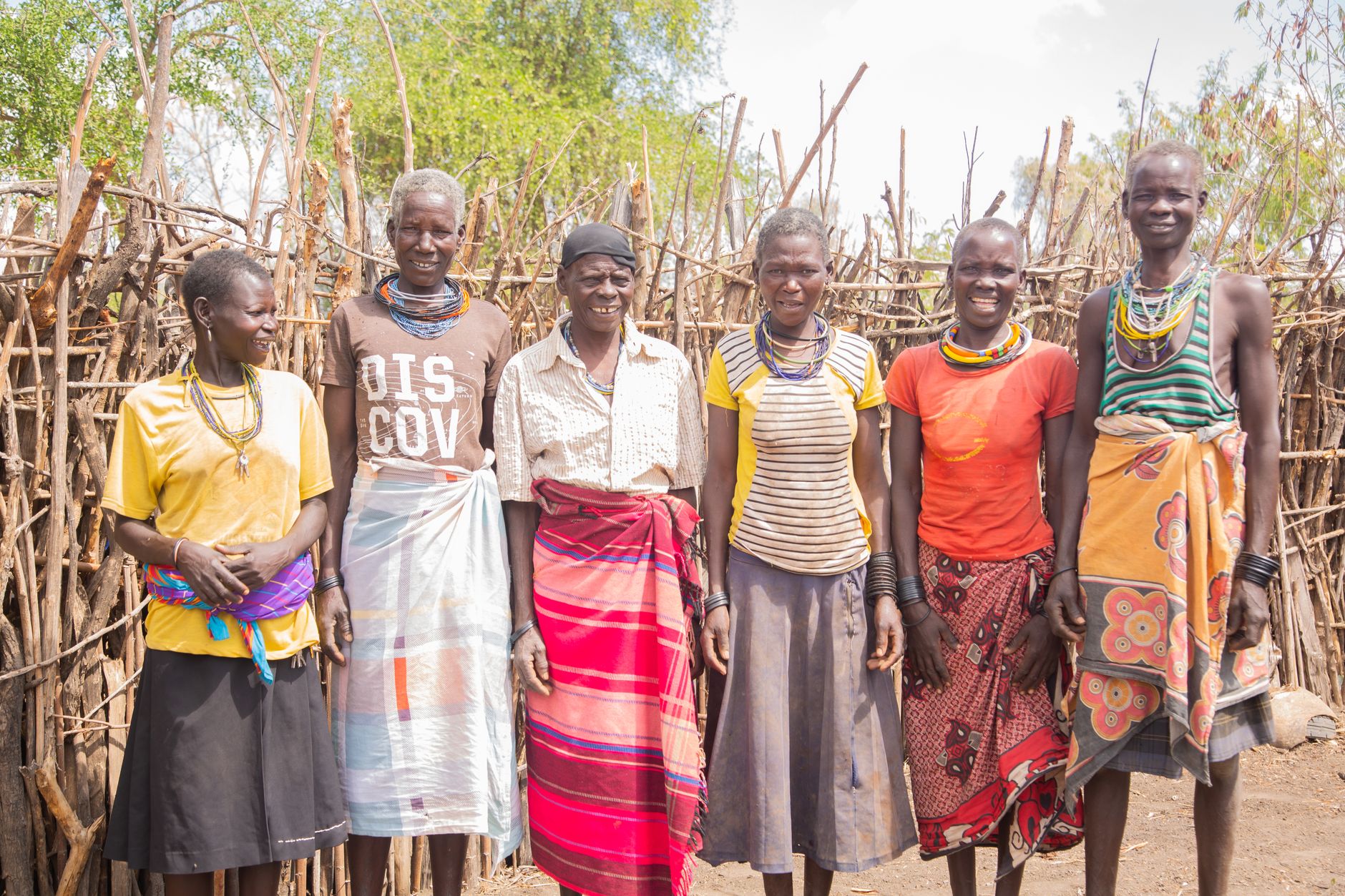Smiling African tribal group in traditional attire outdoors.