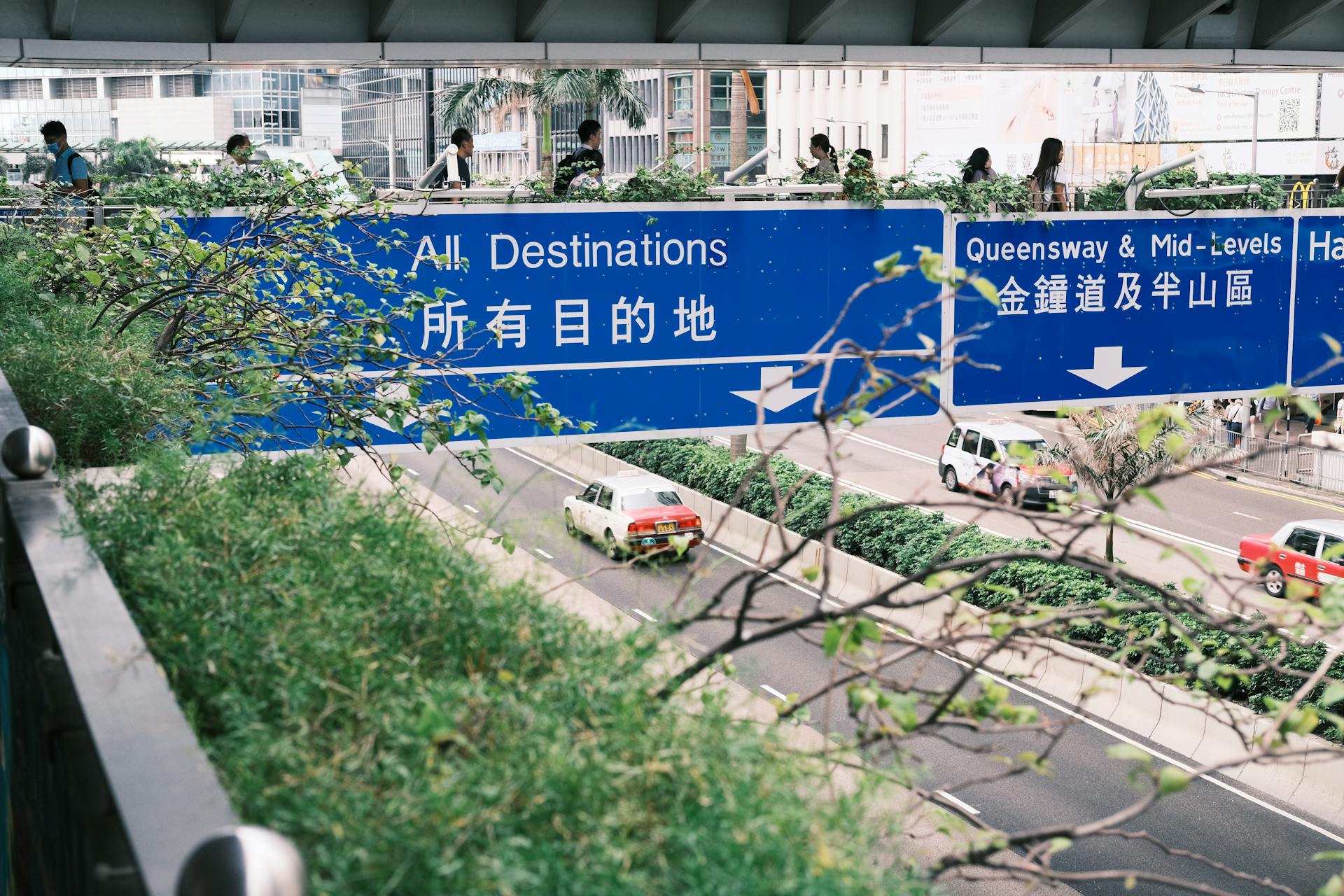 Busy street scene in Hong Kong showing road signs and taxis below.