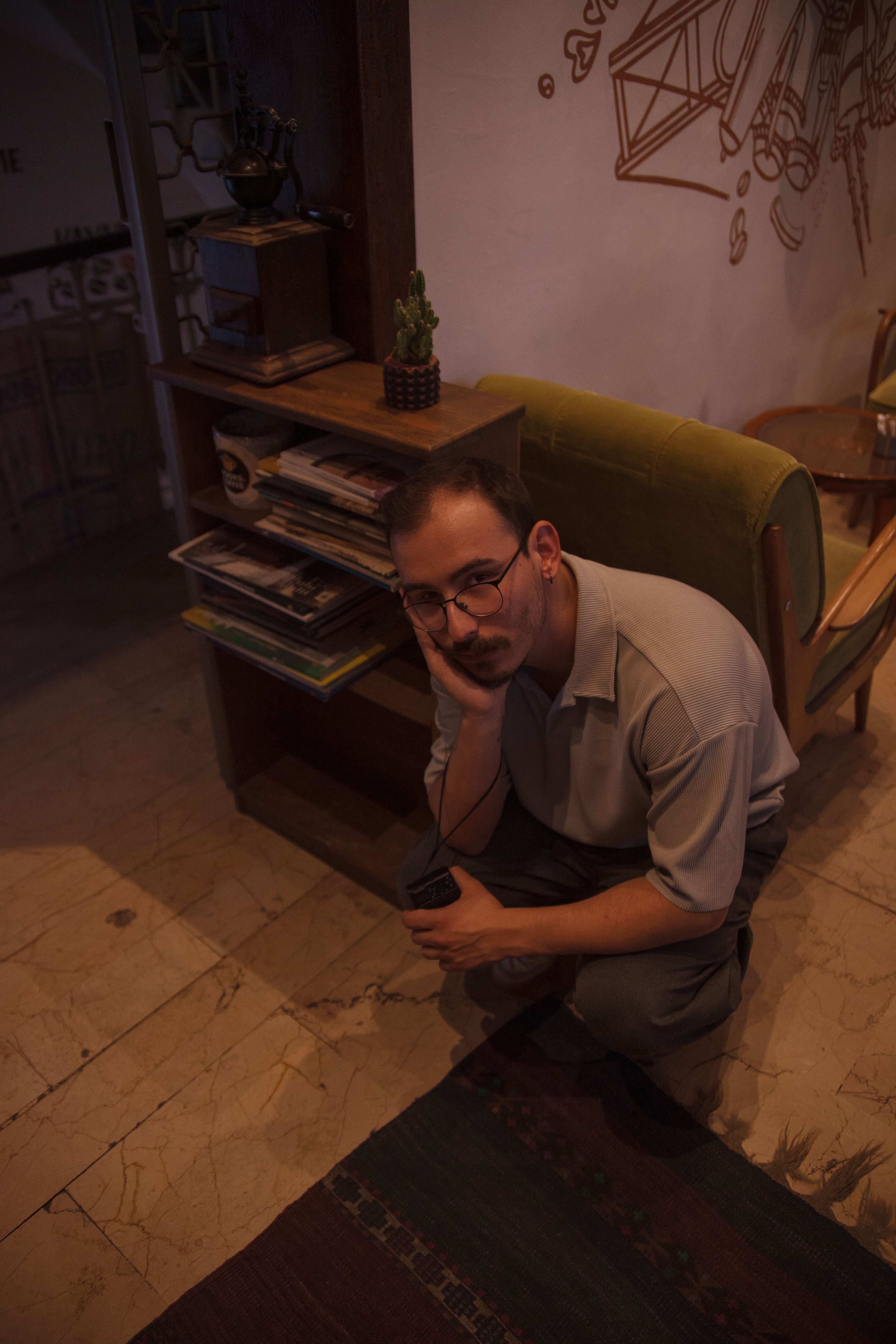 A man crouching down in a room with a coffee cup · Free Stock Photo