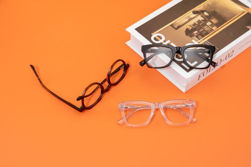 Free Stylish eyeglasses and books on an orange backdrop showcase modern design and fashion. Stock Photo
