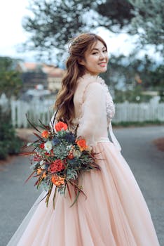 A joyful bride in a pastel dress holding a colorful bouquet outdoors.