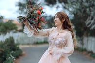 一位身着精致连衣裙的美丽女子在户外手持充满活力的花束，表达喜悦之情