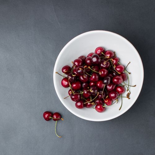 Free A bowl of fresh cherries showcasing their rich, juicy color in a minimalist setting. Stock Photo