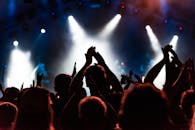 在明亮的舞台灯光下，音乐会观众为充满活力的表演鼓掌欢呼