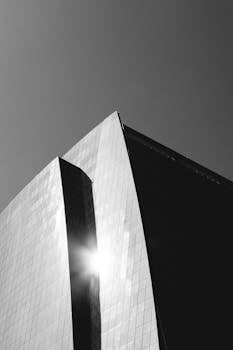 一张引人注目的黑白照片，展现了现代玻璃建筑立面反射阳光的景象