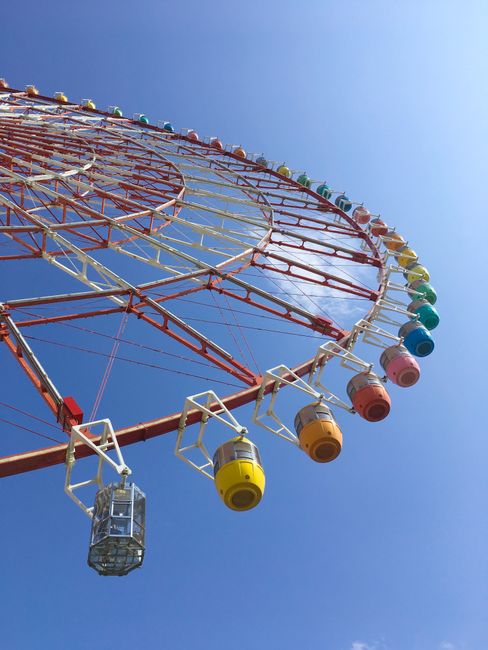Colorful Ferris wheel at a fairground set against a bright blue sky, evoking fun and excitement.