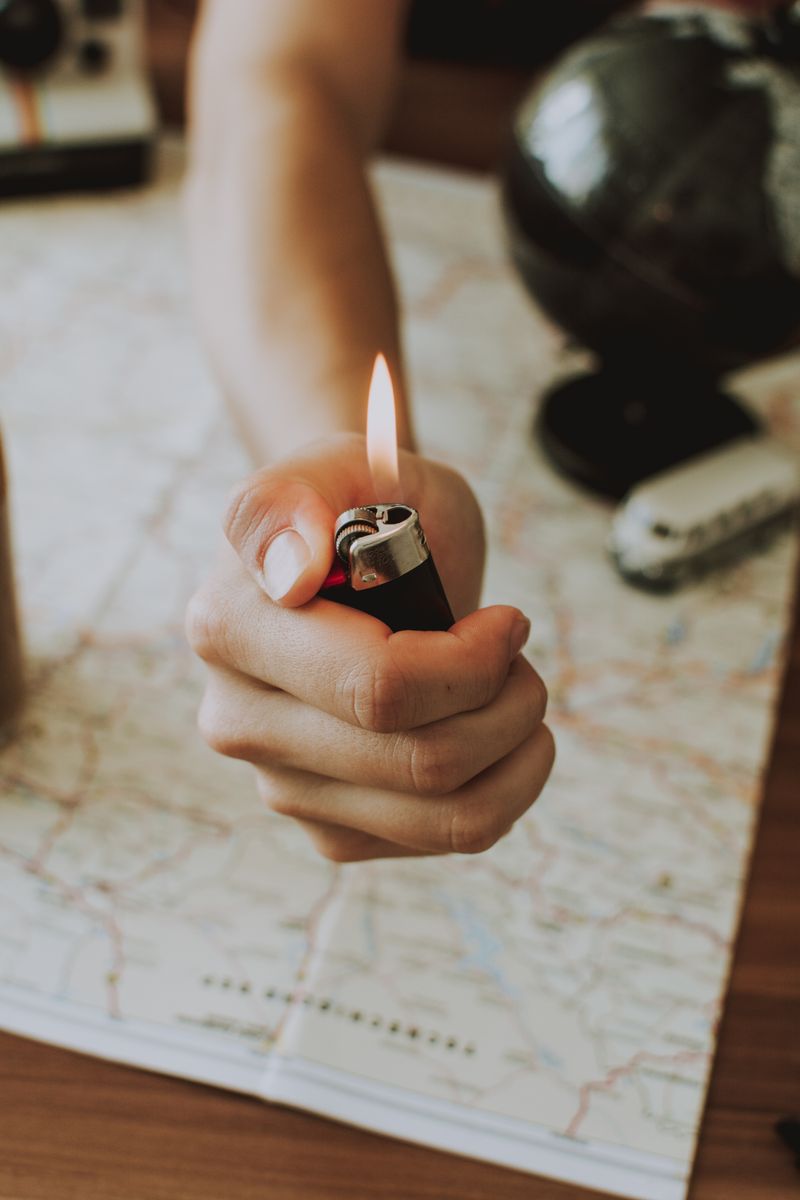A hand holding a lighter over a map, signifying travel plans and adventure.