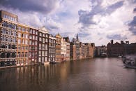 在多云的天空下，阿姆斯特丹的标志性运河旁矗立着色彩缤纷的历史建筑
