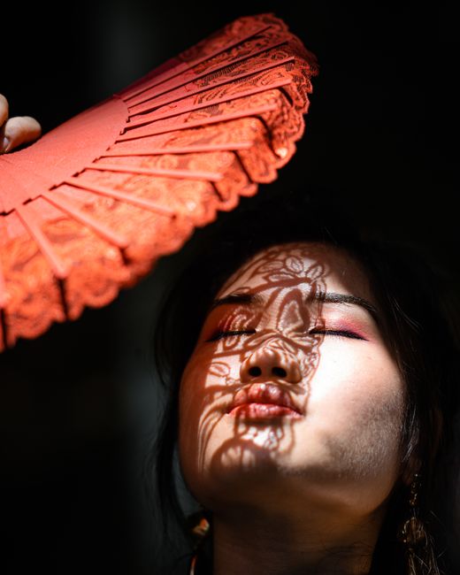 Portrait of an Asian woman with intricate lace shadows cast on her face, captured in Kuala Lumpur.