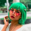 这幅色彩缤纷的肖像捕捉了一位时尚女性，她留着亮绿色头发，戴着反光太阳镜