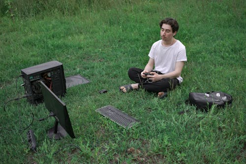 Mann, Der Auf Gras Mit Computer Sitzt