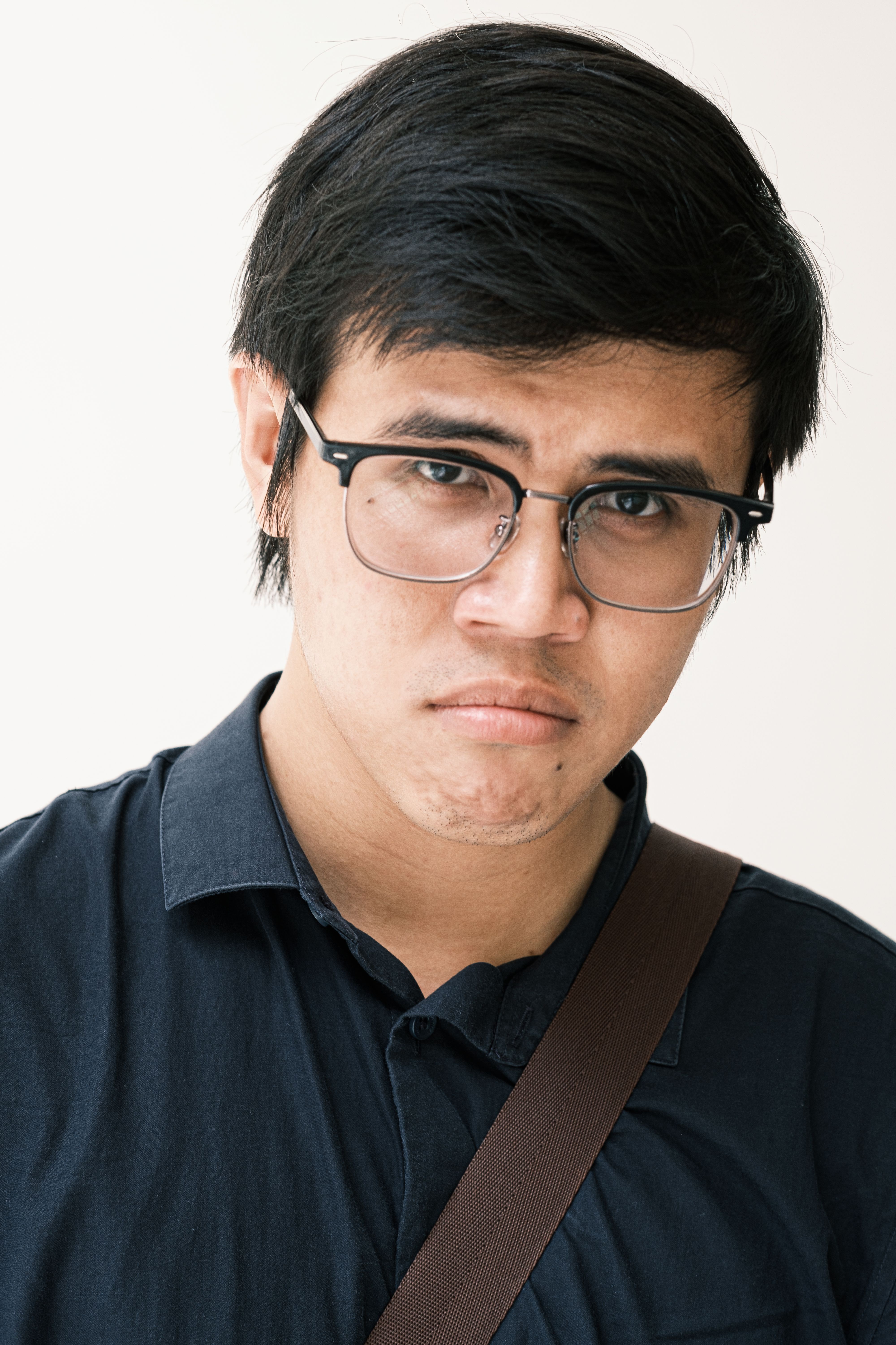 Portrait of a young man wearing eyeglasses, expressing a serious demeanor.