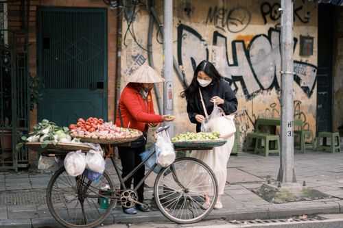Free Urban street vendor selling fruits from a bike to a customer in an Asian city. Stock Photo