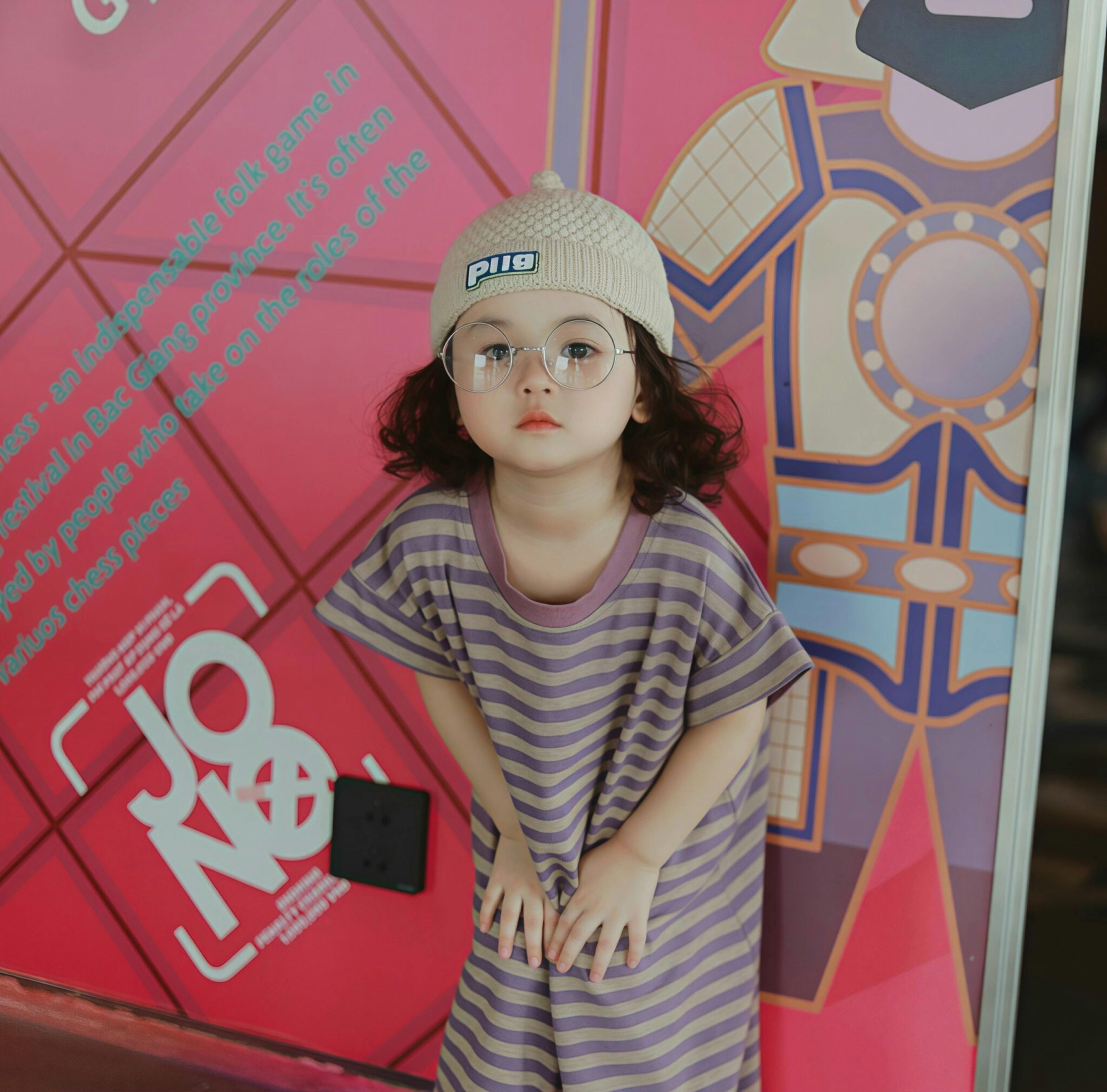 a little girl in a hat and striped shirt