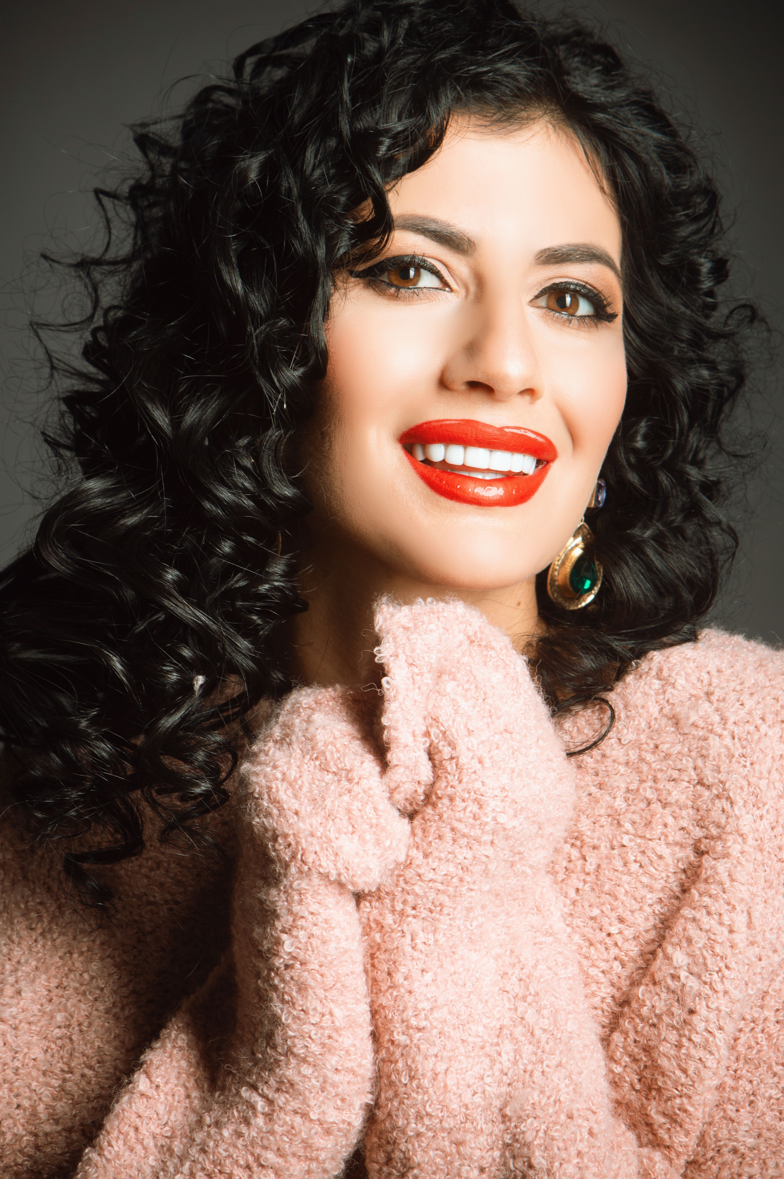 Elegant portrait of a woman with curly hair and vibrant red lipstick, exuding glamour and style.