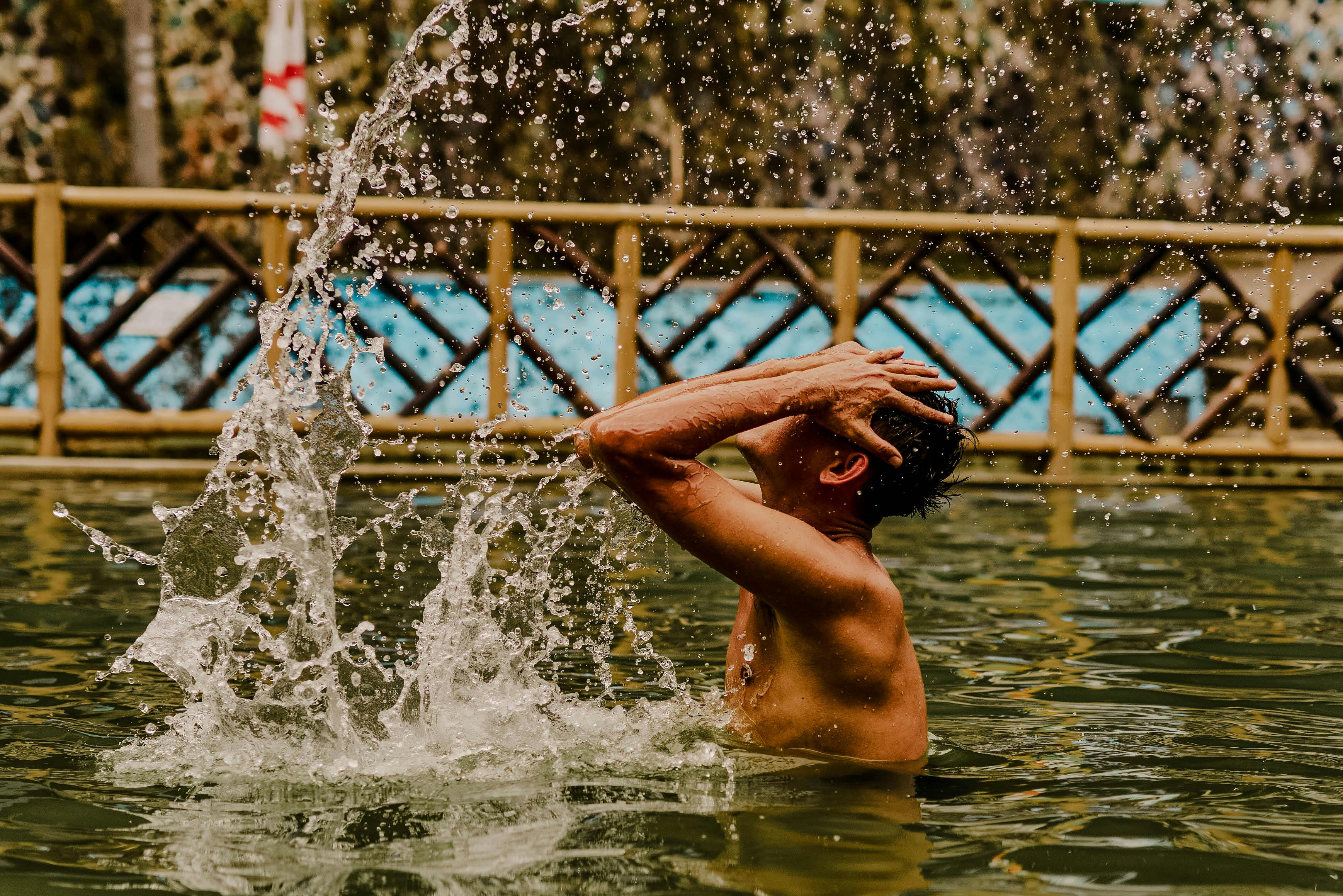 Pessoa adolescente se refrescando na água durante um dia ensolarado ao ar livre.