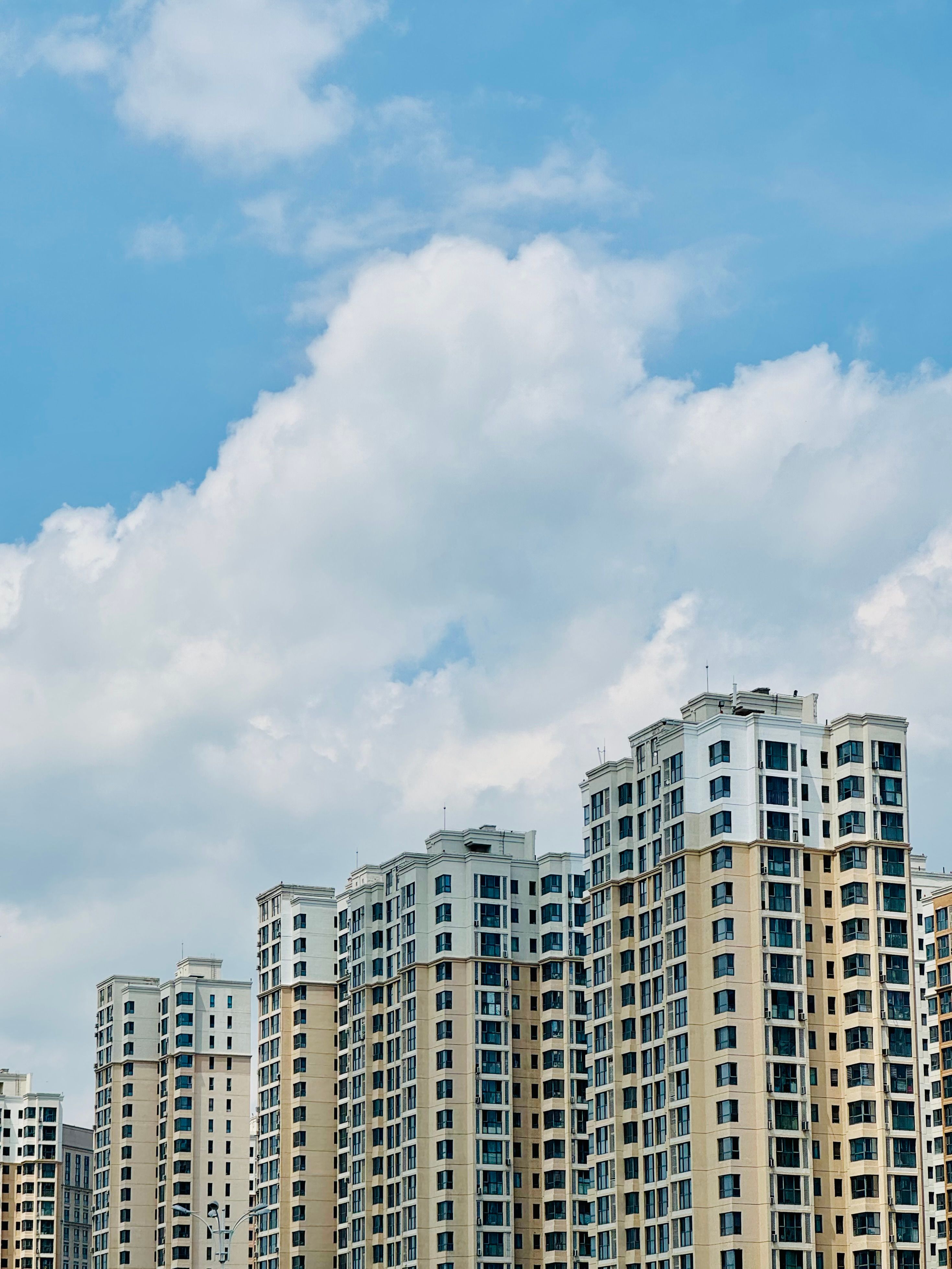 A row of tall buildings with blue sky and clouds · Free Stock Photo