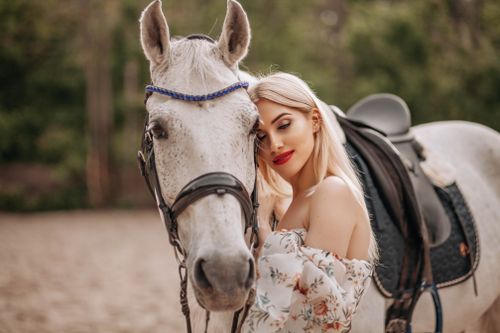 Free A beautiful woman poses lovingly with a white horse in a serene outdoor setting. Stock Photo