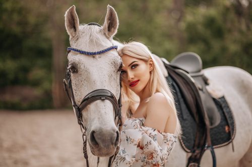 Free A stylish woman embraces a white horse in an outdoor setting, showcasing elegance and nature. Stock Photo